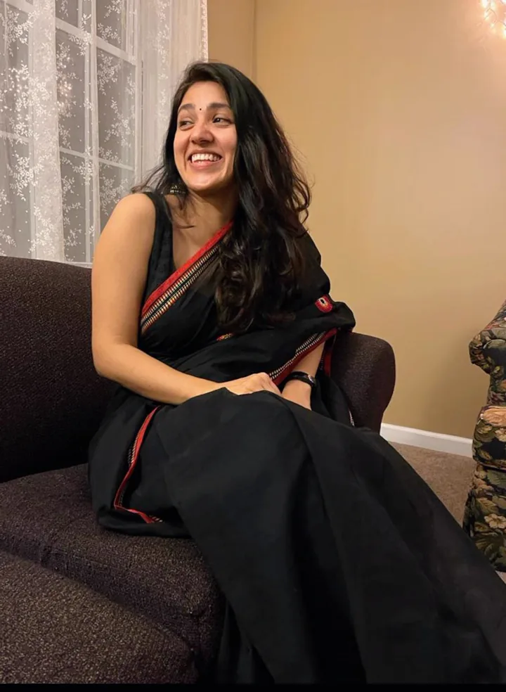 Sarika, the NRI sister, smiling in a black saree