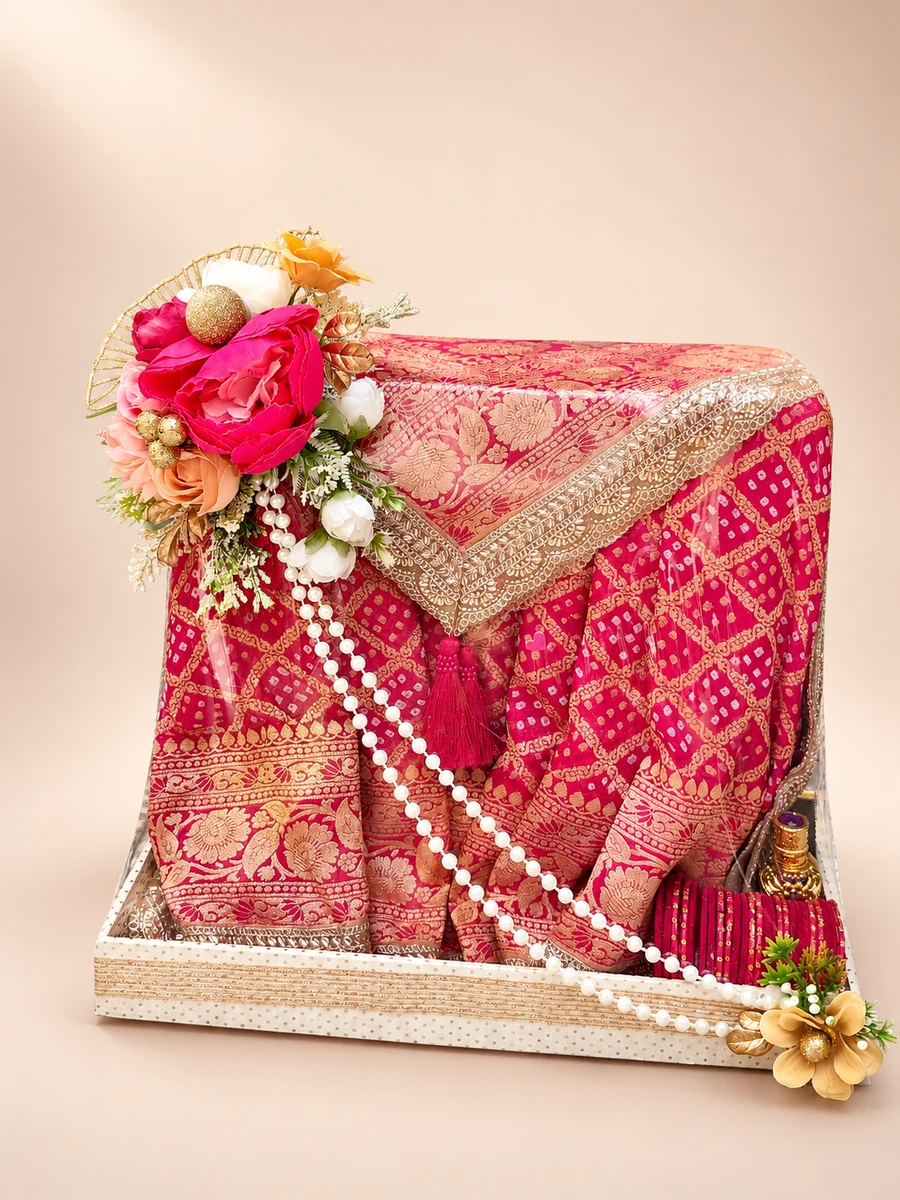 A red and gold bridal trousseau sari with flowers and pearls, arranged in a presentation tray